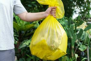 Man Volunteer charity holding garbage yellow bag and plastic bottle garbage for recycling cleaning photo