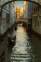 varios góndolas vela en un fila a lo largo el estrecho veneciano canal en el ligero de el ajuste Dom. foto