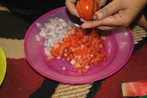 someone is slicing tomatoes in a plate, someone is cutting tomatoes photo