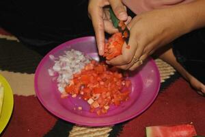 someone is slicing tomatoes in a plate, someone is cutting tomatoes photo