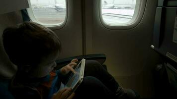 Junge Sitzung im das Flugzeug und mit Tablette pc video