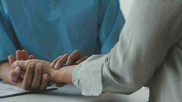 Doctor and patient sitting and talking at medical examination at hospital office, close-up. Therapist filling up medication history records. Medicine and healthcare concept. video