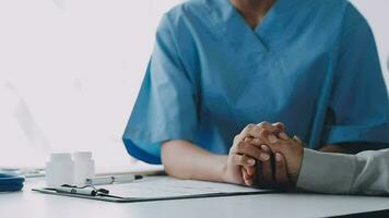 Doctor and patient sitting and talking at medical examination at hospital office, close-up. Therapist filling up medication history records. Medicine and healthcare concept. video