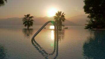une steadicam coup de un ouvert nager bassin et une le coucher du soleil par le mer video