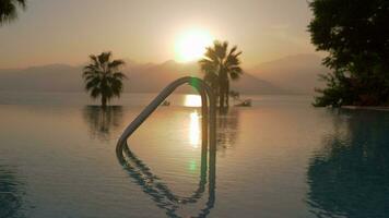 A steadicam shot of an open swimming pool and a sunset by the sea video