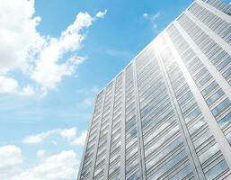 Bottom up view modern office tower building with blue sky background photo