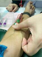 A nurse drawing blood from patient vein photo