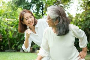 An old elderly Asian woman and exercise in the backyard with her daughter.  Concept of happy retirement With care from a caregiver and Savings and senior health insurance, Happy family photo