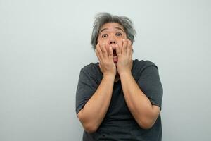 Portrait of a furious senior grey-haired man yelling and screaming and gesturing in fear with hands and face on isolated background photo