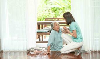 Asian senior woman falling down on lying floor at home after Stumbled at the doorstep and Crying in pain and the nurse came to help support. Concept of old elderly insurance and health care photo