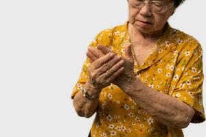 Elderly Asian woman patients suffer from numbing pain in hands from rheumatoid arthritis. Senior woman massage her hand with wrist pain. Concept of joint pain, rheumatoid arthritis, and hand problems. photo