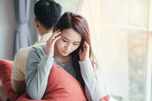 Unhappy Couple sitting behind each other on the couch and avoid talking or looking at each other, Cause of relationship problems and having misunderstanding or disagreement. Family problems concept photo