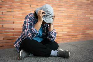pobre cansado estresado Deprimido mayor asiático mujer Vagabundo sentado en el calle en el sombra de el edificio y mendicidad para ayuda y dinero, mayor asiático mujer abandonado concepto foto
