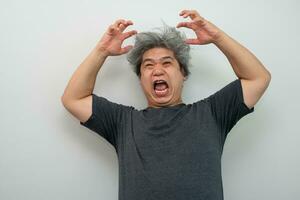 Portrait of a furious senior grey-haired man yelling and screaming and gesturing in fear with hands and face on isolated background photo