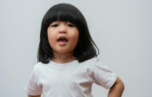 Portrait of happy and funny Asian child girl on white background, a child looking at camera hand gesture. Preschool kid dreaming fill with energy feeling healthy and good concept photo