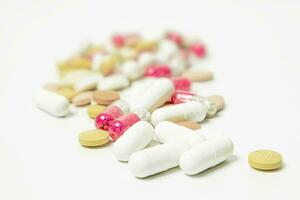 Pills and capsules on white background. Focus on foreground, soft bokeh. photo