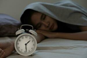 asiático mujer en cama tarde molesto a dormir sufrimiento insomnio, insomne o asustado en un pesadilla, mirando triste preocupado y estresado. cansado y dolor de cabeza o migraña despertar arriba en el medio de el noche. foto