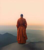 Buddhist monk standing on mountaintop at beautiful sunset or sunrise photo