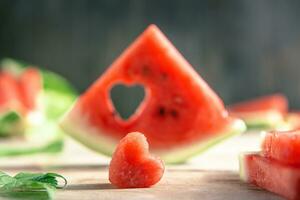 A cut piece of watermelon with a heart-shaped hole. Summer, joy, happiness, delicious food photo