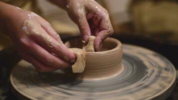 Potter girl works on potter's wheel, making ceramic pot out of clay in pottery workshop photo