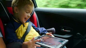 pequeño chico jugando en tableta computadora en el coche video