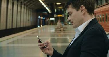 jovem bonito homem de negocios mensagens de texto em célula dentro metrô video