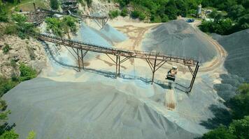 Arial vue de le le sable fabrication plante dans mine à ciel ouvert exploitation minière. drone mouches plus de pelles et tracteur chargement écrasé pierre et Roche dans déverser camion. 4k Stock images. video