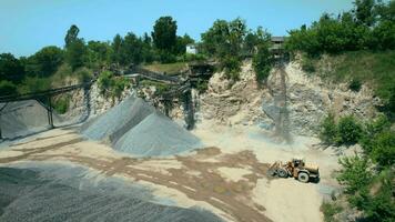 arial Aussicht von das Sand Herstellung Pflanze im Tagebau Bergbau. Drohne fliegt Über Bagger und Traktor Wird geladen zerquetscht Stein und Felsen in Dump LKW. 4k Lager Filmaufnahme. video