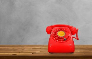 Red vintage desk phone on wooden table, cement background. photo
