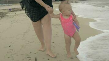 Mum with baby daughter walking barefoot on the beach video