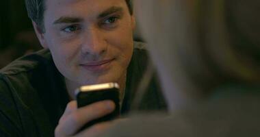 Young man with pleased smile texting on cell phone video