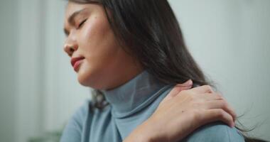 Footage of young asian woman suffering with neck pain massaging her neck while working video