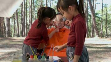 contento madri e bambini trascorrere inverno vacanze insieme nel un' pino foresta, colorazione pino coni per decorare il Natale albero. Natale mestiere attività per bambini a partire dal pino coni. video