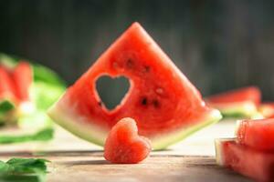 A cut piece of watermelon with a heart-shaped hole. Summer, joy, happiness, delicious food photo