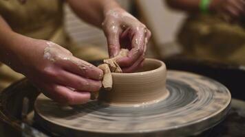 Potter girl works on potter's wheel, making ceramic pot out of clay in pottery workshop photo