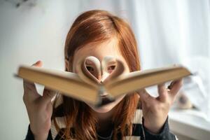 un niña es participación un libro. en forma de corazon paginas lectura, conocimiento, aprendizaje foto