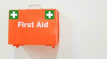 First aid kit orange box on wall at office isolated on white background with copy space for text. photo