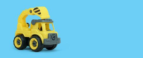 Yellow plastic truck toy isolated on blue background. construction vechicle truck. a copy space for banner of toy store. photo