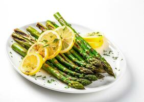 Freshly grilled asparagus spears with lemon slices isolated on a white background photo