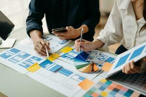 UX developer and ui designer brainstorming about mobile app interface wireframe design with customer breif and color code at office. photo