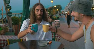 dos amigos hablando en café en frente al mar video