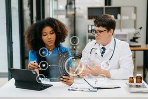 Doctor Talks With Professional Head Nurse or Surgeon, They Use Digital tablet Computer. Diverse Team of Health Care Specialists Discussing Test Result on desk photo