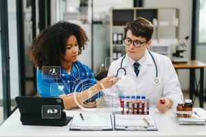 Doctor Talks With Professional Head Nurse or Surgeon, They Use Digital tablet Computer. Diverse Team of Health Care Specialists Discussing Test Result on desk photo
