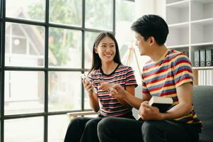 Two asian students learning together online with a laptop, tablet and tutor together in living room photo