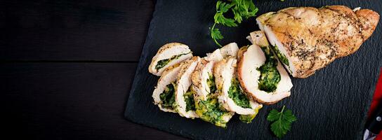 Roasted sliced Christmas roll of turkey with spinach and cheese on dark rustic background. Top view, copy space. Banner. Festival food. photo