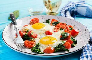 plato con un ceto dieta alimento. frito huevo, espinaca, y Tomates. ceto, paleo desayuno. foto