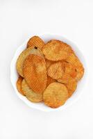 Red pieces of fried potatoes in a plate. Peppery chips on a white background. photo