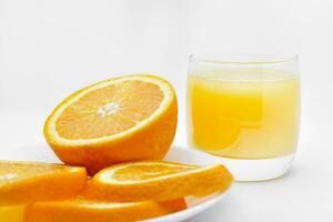 naranja jugo en un vaso vaso y el Fruta de naranjas refrescante bebida en un blanco antecedentes de fruta. foto