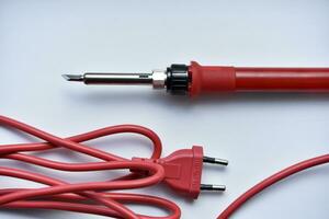 Red soldering iron on a white background. A tool for repairing electronics. photo