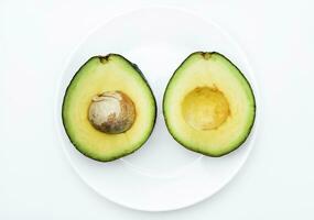 Sliced green avocado on a white background. Pieces of green vegetable on a white plate. Delicious food for a vegan. photo